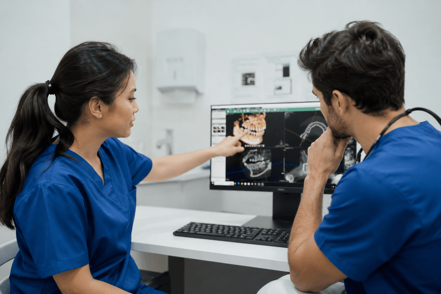Two dentists reviewing a dental scan together at a workstation