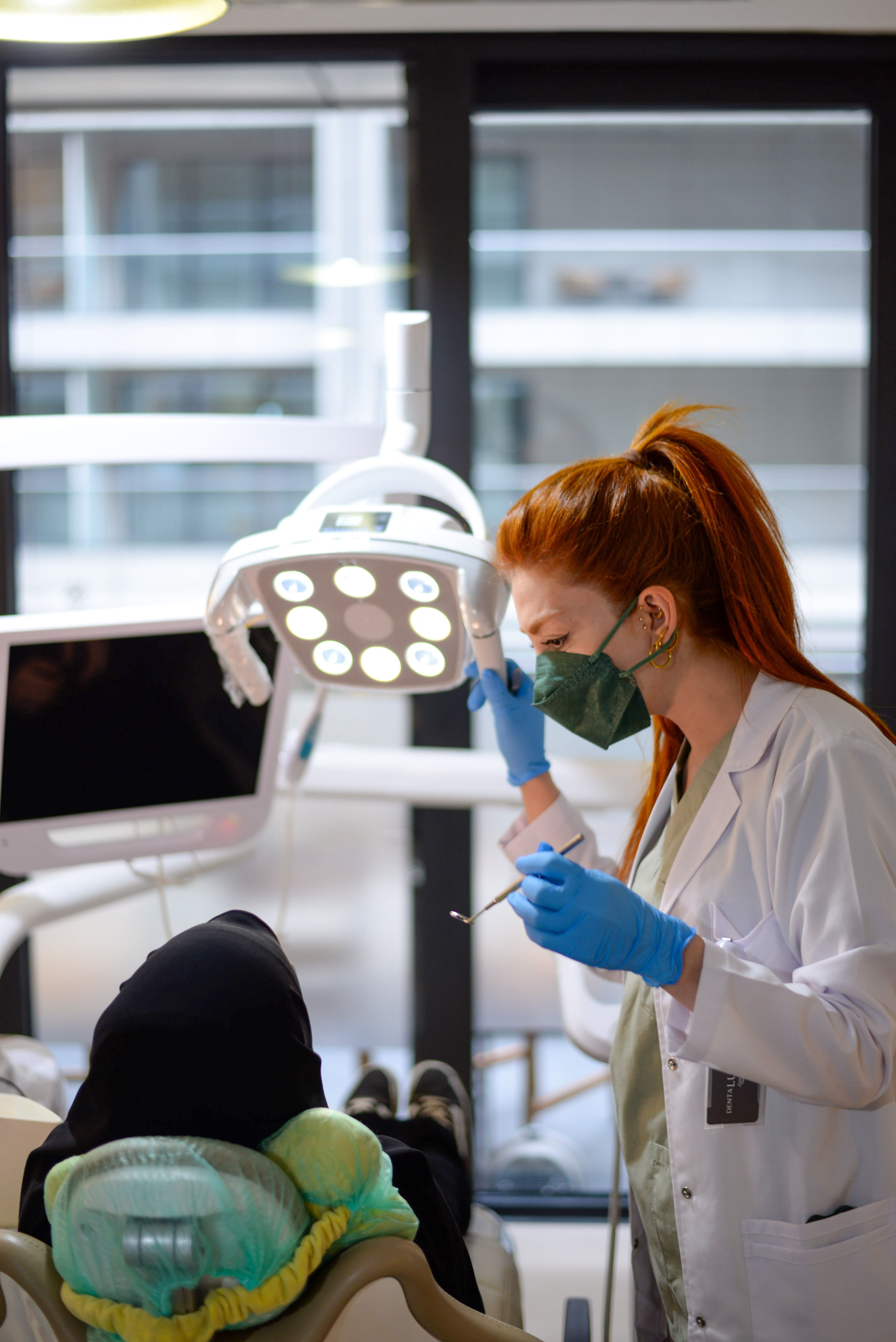 Dentist focused on patient care under an operatory light